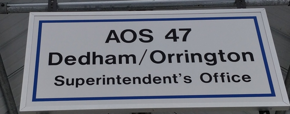 image of the sign at the Superintendents office that reads "AOS 47 Dedham/Orrington Superintendents Office" white sign with a navy blue border and black text